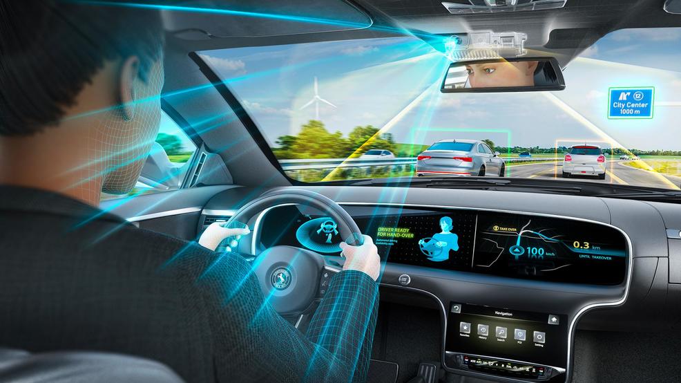 Interior of a modern vehicle showing driver monitoring cameras and sensor arrays embedded in the dashboard and steering wheel