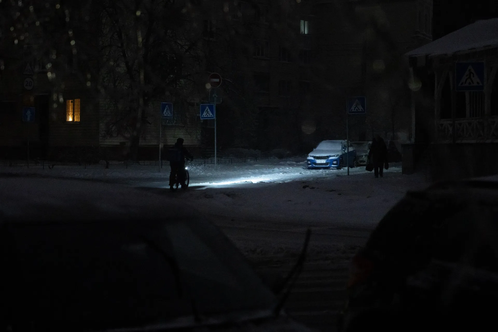 A person rides a bicycle on a non-illuminated street during a power outage in Kyiv, Ukraine